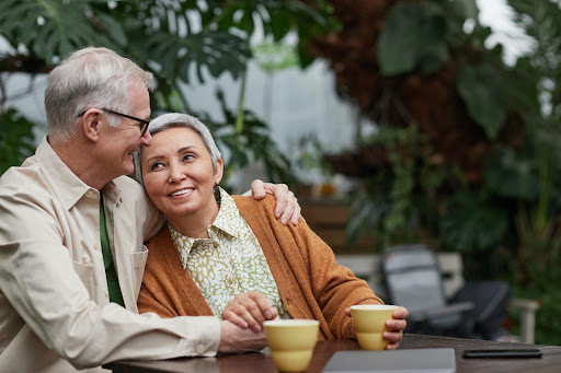 An older couple enjoying a cup of coffee in a garden while discussing their Medicare insurance coverage.